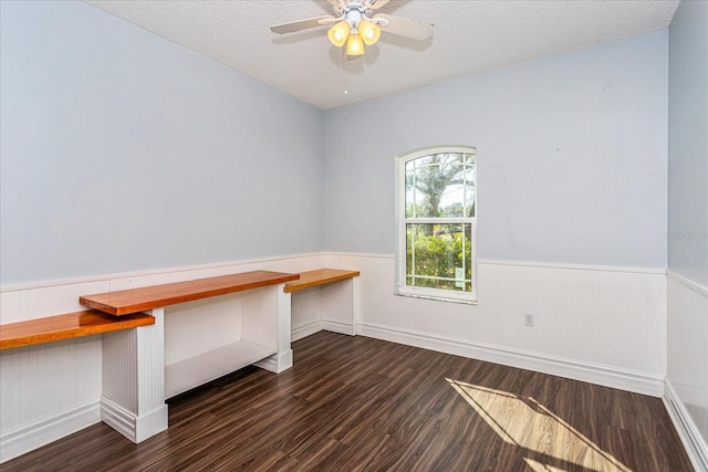 unfurnished office with dark hardwood / wood-style flooring, a textured ceiling, and ceiling fan