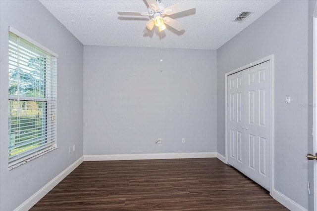 unfurnished bedroom with multiple windows, ceiling fan, a closet, and dark hardwood / wood-style flooring