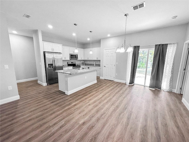 kitchen featuring appliances with stainless steel finishes, sink, pendant lighting, white cabinetry, and an island with sink