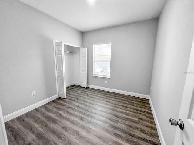 unfurnished bedroom with a closet and dark wood-type flooring