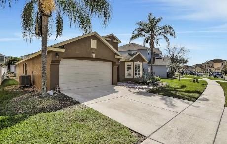 view of front of house with a front yard, a garage, and central air condition unit