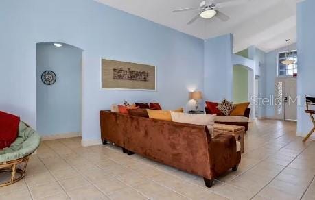 living room with ceiling fan, lofted ceiling, and light tile patterned floors