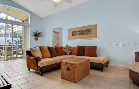 living room with ceiling fan, lofted ceiling, and light tile patterned flooring