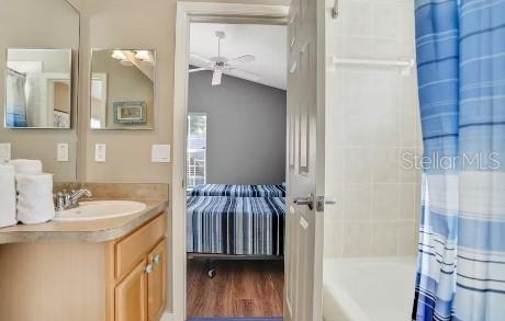 bathroom with hardwood / wood-style floors, vanity, ceiling fan, and shower / bath combo with shower curtain