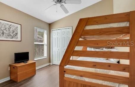 bedroom with ceiling fan, dark hardwood / wood-style floors, lofted ceiling, and a closet