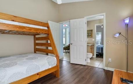 bedroom with ensuite bath, radiator heating unit, and dark hardwood / wood-style floors