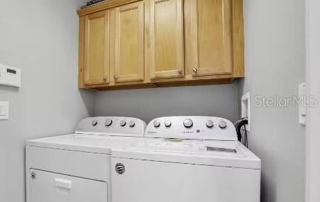 clothes washing area featuring cabinets and washing machine and clothes dryer