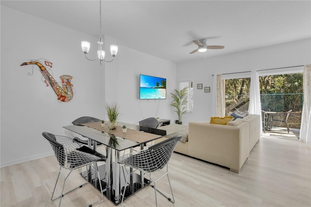 dining area with ceiling fan with notable chandelier and light hardwood / wood-style flooring