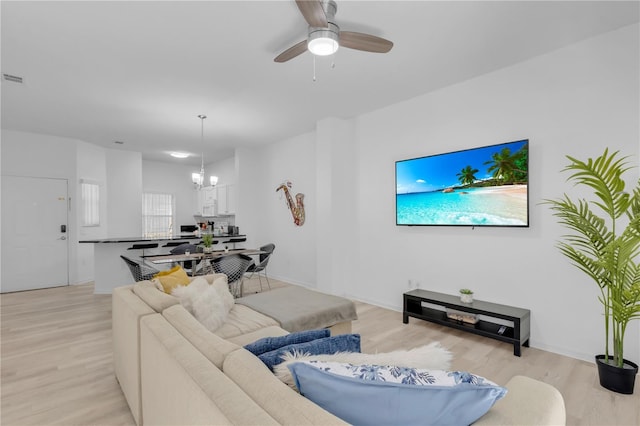 living room featuring ceiling fan with notable chandelier and light hardwood / wood-style flooring