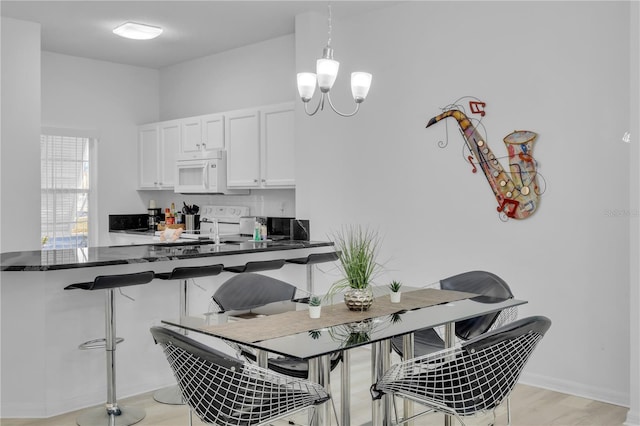 kitchen featuring stove, white cabinets, light hardwood / wood-style flooring, decorative backsplash, and decorative light fixtures