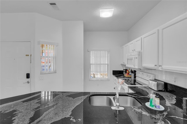 kitchen with white appliances, backsplash, dark stone counters, white cabinets, and sink