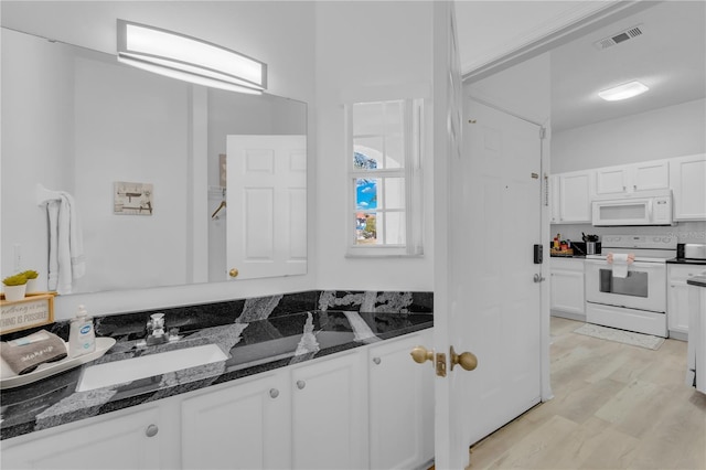 kitchen featuring white appliances, sink, dark stone countertops, white cabinets, and light hardwood / wood-style floors