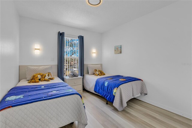 bedroom with light wood-type flooring and a textured ceiling