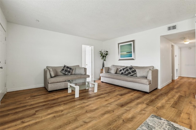 living room featuring wood-type flooring and a textured ceiling