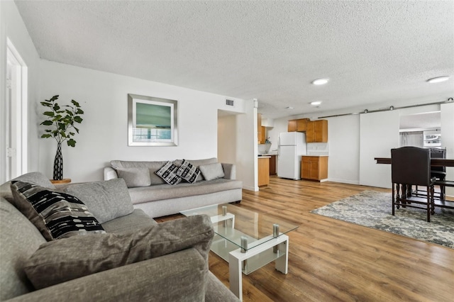 living room featuring a barn door, a textured ceiling, and light wood-type flooring