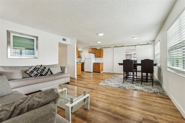 living room with a barn door, light hardwood / wood-style floors, and a textured ceiling