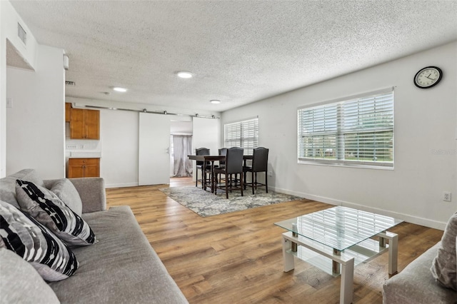 living room featuring a barn door, a textured ceiling, and light wood-type flooring