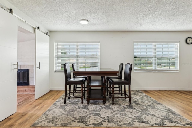 dining room featuring hardwood / wood-style floors, a barn door, a textured ceiling, and a healthy amount of sunlight