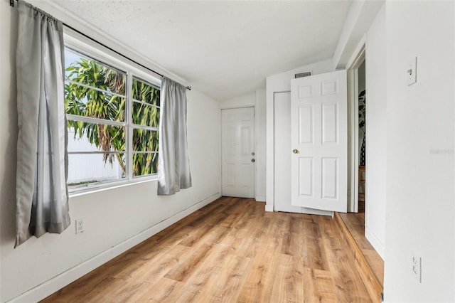 unfurnished bedroom with multiple windows, light hardwood / wood-style flooring, and vaulted ceiling