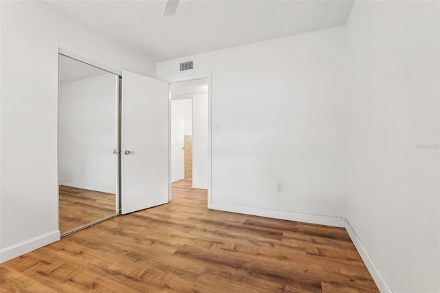 unfurnished bedroom with ceiling fan, wood-type flooring, and a closet