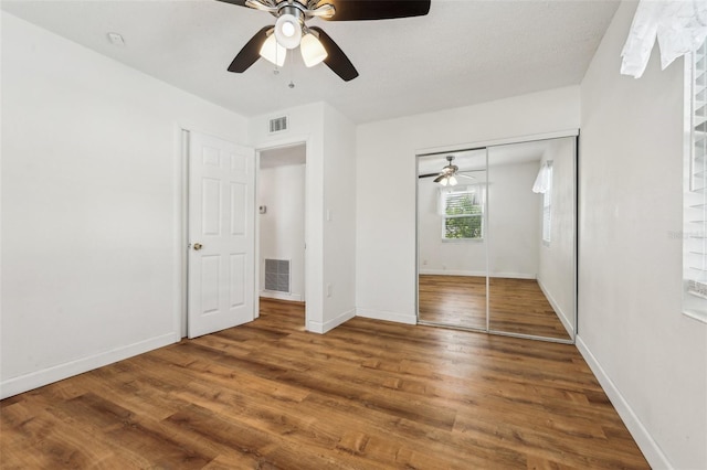 unfurnished bedroom featuring wood-type flooring, a closet, and ceiling fan