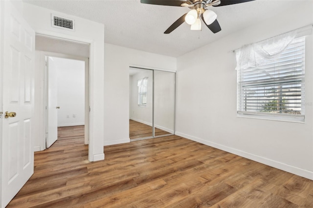 unfurnished bedroom featuring ceiling fan, a closet, and wood-type flooring