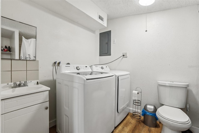 laundry area featuring a textured ceiling, independent washer and dryer, sink, hardwood / wood-style floors, and electric panel