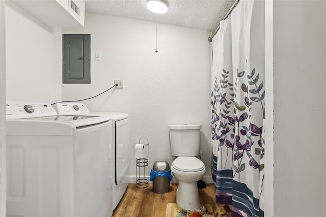 bathroom featuring washer and clothes dryer, hardwood / wood-style floors, electric panel, toilet, and a textured ceiling