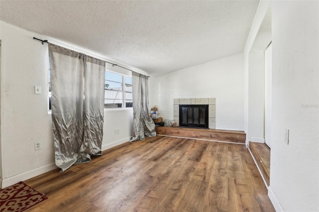 unfurnished living room with hardwood / wood-style flooring, a textured ceiling, and a tile fireplace