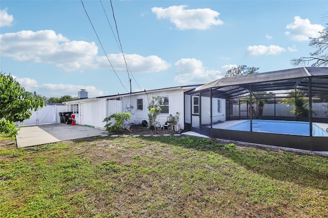 rear view of property featuring glass enclosure, a patio area, and a yard