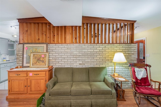 living room featuring brick wall and light hardwood / wood-style floors