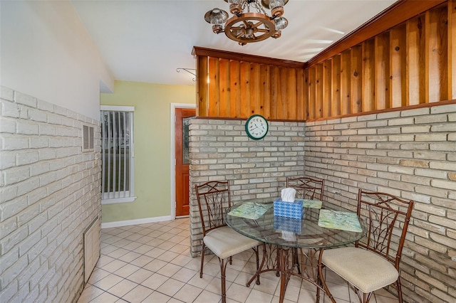 tiled dining room featuring brick wall and an inviting chandelier