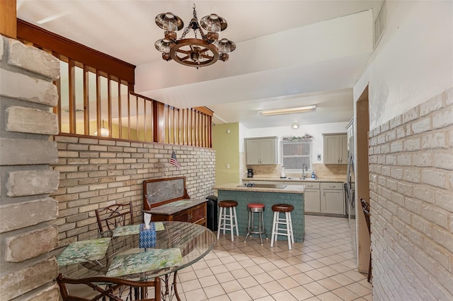 kitchen featuring sink, a kitchen bar, tasteful backsplash, light tile patterned flooring, and kitchen peninsula