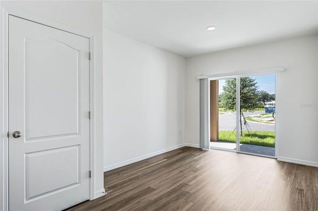 spare room featuring dark wood-style flooring, recessed lighting, and baseboards