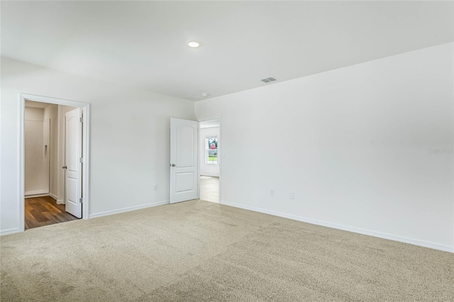 spare room featuring dark colored carpet, visible vents, and baseboards