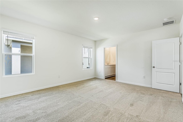 unfurnished bedroom featuring visible vents, baseboards, carpet flooring, and ensuite bathroom