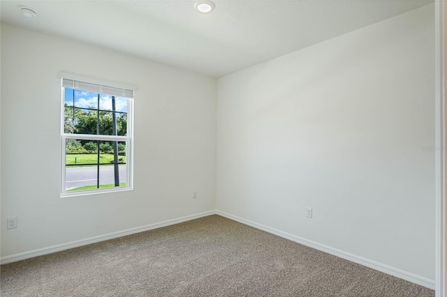 spare room featuring carpet flooring and baseboards