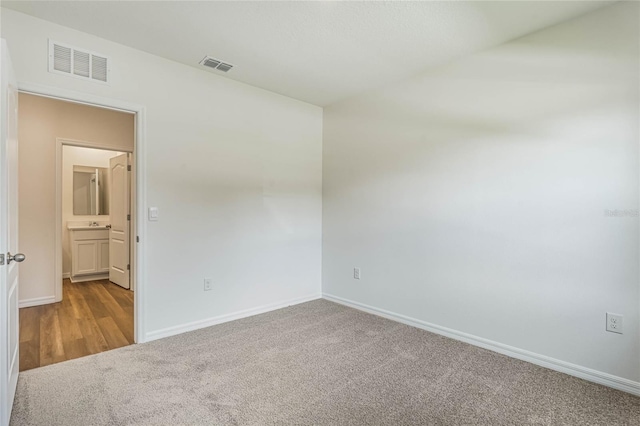 carpeted spare room with visible vents and baseboards