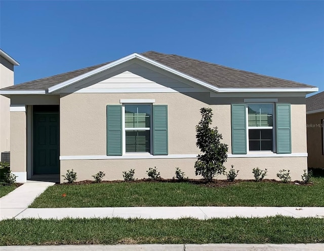 view of front of property featuring a shingled roof, a front lawn, and stucco siding