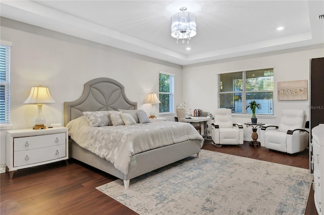 bedroom with a raised ceiling and dark wood-type flooring