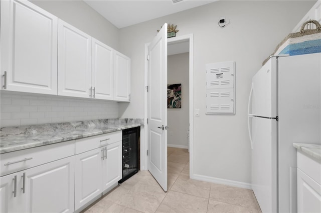 kitchen featuring light stone countertops, white refrigerator, white cabinetry, and beverage cooler