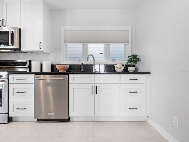 kitchen with sink, white cabinets, stainless steel appliances, and light tile patterned floors