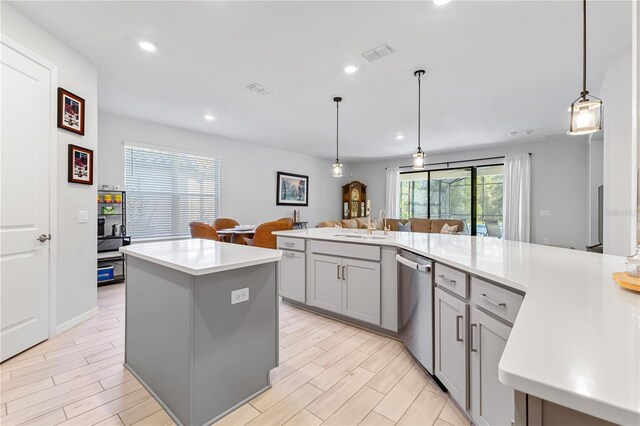 kitchen with sink, pendant lighting, dishwasher, gray cabinets, and a kitchen island