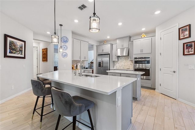 kitchen featuring sink, stainless steel appliances, pendant lighting, gray cabinets, and decorative backsplash