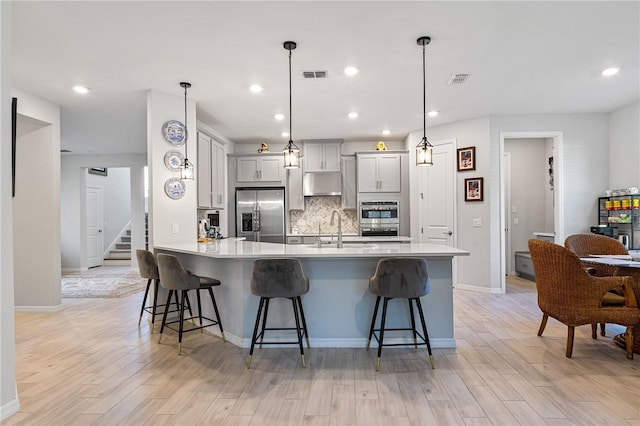 kitchen featuring a kitchen breakfast bar, hanging light fixtures, appliances with stainless steel finishes, and tasteful backsplash