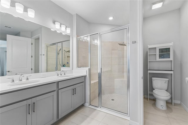 bathroom with toilet, vanity, tile patterned floors, and a shower with shower door