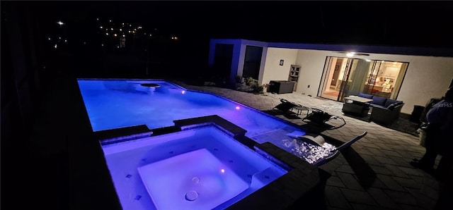 pool at twilight featuring an in ground hot tub and a patio