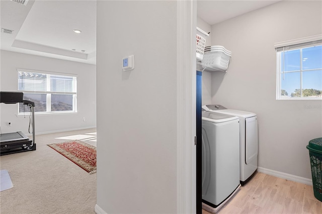 laundry area with independent washer and dryer and light hardwood / wood-style flooring