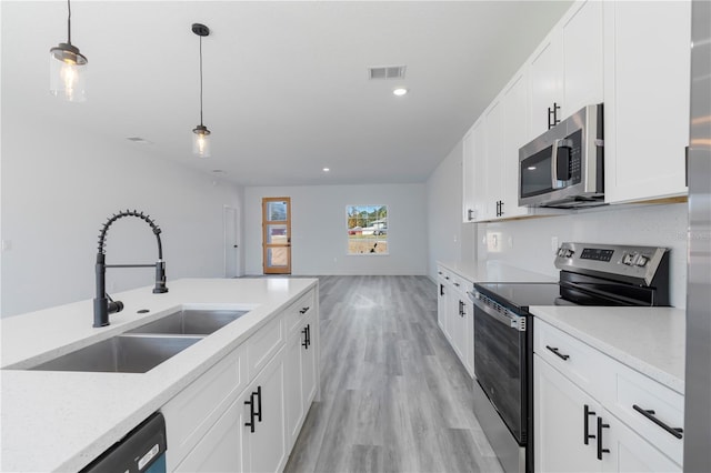 kitchen with sink, hanging light fixtures, light wood-type flooring, white cabinetry, and stainless steel appliances