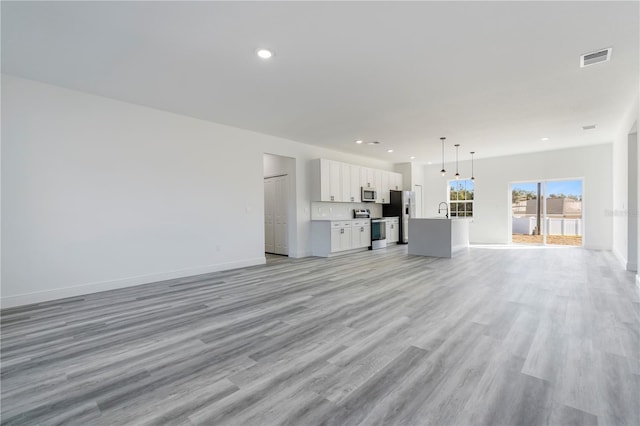 unfurnished living room with sink and light hardwood / wood-style flooring